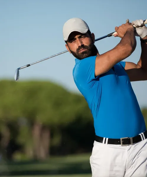 Golfer in blue polo shirt with golf bag smiling on the golf course